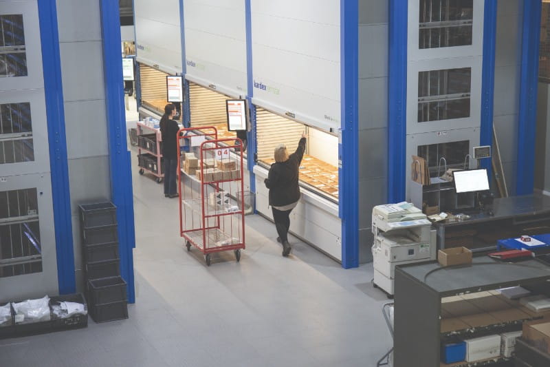 Warehouse with Kardex machines, two warehouse operatives picking stock