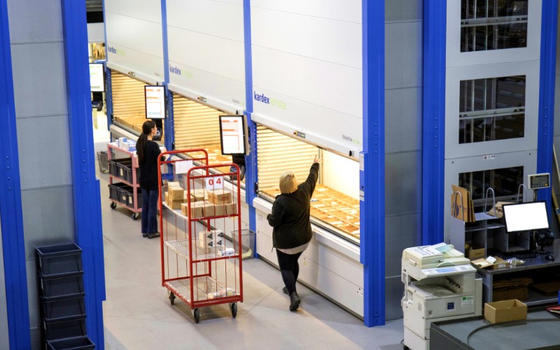 Warehouse with Kardex machines, two warehouse operatives picking stock
